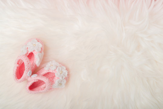 Close up Baby girl knitted shoes on white blanket background.Happy new year greeting card with copy-space. New born celebration holiday concept.