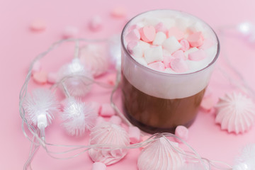 Obraz na płótnie Canvas Hot beverage with whipped cream,marshmallows and heart shaped chocolate candies on pink pastel background