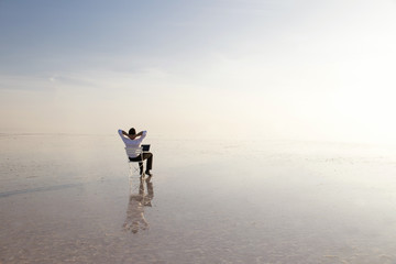 Business man with laptop working on the beach