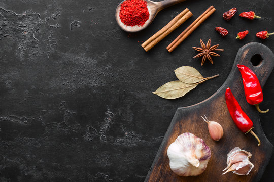 cutting board with spices and herbs on a black background and space for text