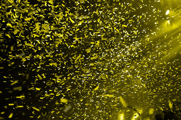 Confetti fired on air during a concert. People are happy with hands in the air. Image ideal for backgrounds. Yellow is the tone of the picture