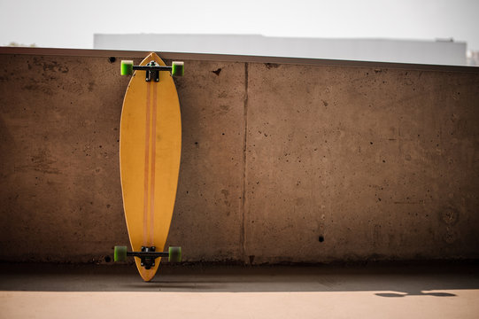Photo of the flat yellow longboard with green wheels