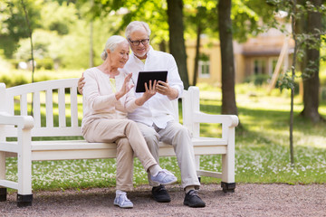 Obraz premium senior couple with video chat on tablet pc at park
