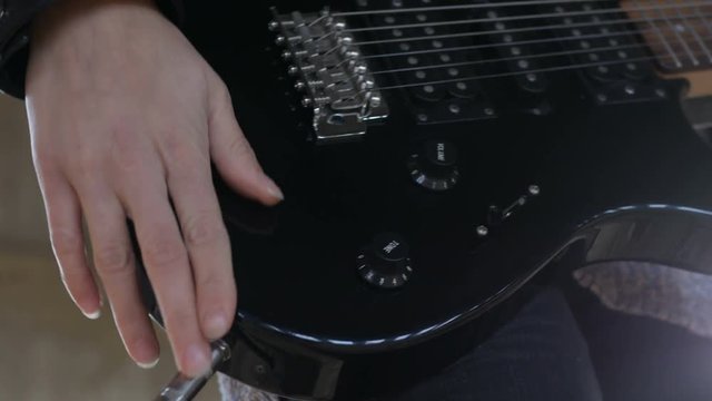 Close up of guitarist's hand plugging audio cable in electric guitar and Tuning the volume and tone knobs