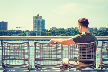 Empty Chairs for You. lonely man seeking friendship. Wearing green T shirt, short haircut, a young lonely guy sitting on chair by Hudson River in New York, facing New Jersey, waiting for you..
