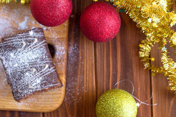 Christmas chocolate roll on a wooden table with red and gold balls Christmas toys