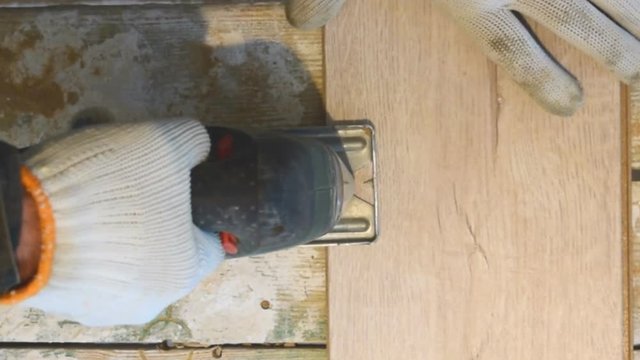 The man cuts the laminate panel with an electric jigsaw.