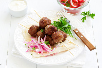 Lamb kebabs on skewers with onion and buttermilk sauce.