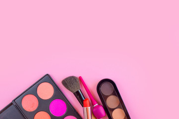 Lipstick, eye shadow, eyeliner cosmetics for girl on pink table background
