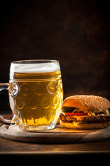 A glass of fresh cold light beer with gourmet hamburgers and wheat in a bar and a dark pub