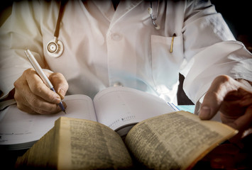 Doctor writes on a book of ancient medicine, conceptual image