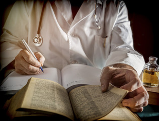 Fototapeta na wymiar Doctor writes on a book of ancient medicine, conceptual image