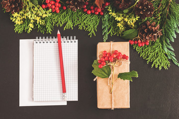 Christmas background or Xmas card. Preparation for winter holiday. A notebook on the black table, flat lay style. Planning concept. Top view. Festive mood
