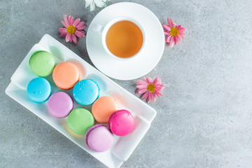 Photo of cake macarons, gift box, tea, coffee, cappuccino and flowers. Sweet romantic food macaroon concept. Morning breakfast and presents.