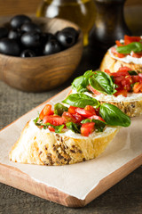 Tomato and cheese fresh made bruschetta. Italian tapas, antipasti with vegetables, herbs and oil on grilled ciabatta and baguette bread.