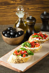 Tomato and cheese fresh made bruschetta. Italian tapas, antipasti with vegetables, herbs and oil on grilled ciabatta and baguette bread.