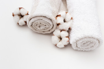 Obraz na płótnie Canvas Spa concept. Two fluffy towels twisted coil and cotton flowers on light white background.