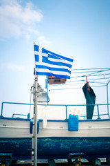 Greek Flag, Blue Sky And Greek Fishing Boat In The Background In Blue Color In Palaria Katerini, Greece