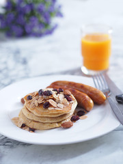 Breakfast Pancake and Sausage Top with Almond and Raisin on white plate