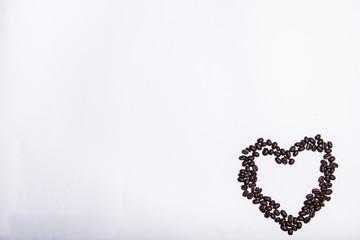 Morning coffee, the concept of still life. An inscription made of coffee beans on a white background next to a cup of coffee. Heart made of coffee beans and inscription love