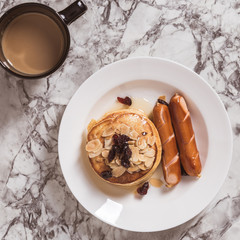 Breakfast Pancake and Sausage Top with Almond and Raisin on white plate