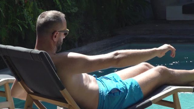 Man applying suntan cream before sunbathing, steadycam shot, slow motion shot at 240fps
