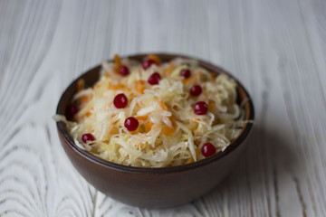 sauerkraut with cranberries in a clay plate on a wooden table