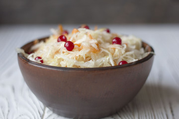 sauerkraut with cranberries in a clay plate on a wooden table