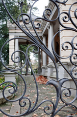 Iron gate and neoclassical house at background. Autumn environment.