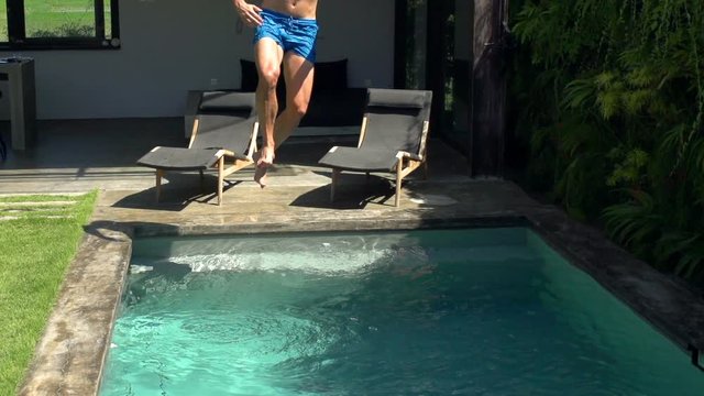 Man jumping to the swimming pool and splashing water, steadycam shot, slow motion shot at 240fps

