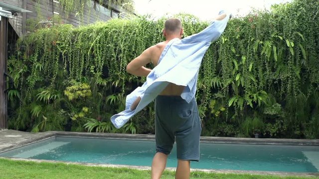 Man walking in the garden and puts shirt on, steadycam shot, slow motion shot at 240fps

