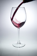pouring of wine in goblet on grey background