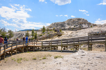 Fototapeta na wymiar Tourists on boardwalk at Palette Spring area, Mammoth Hot Springs Terraces. Yellowstone Park, USA