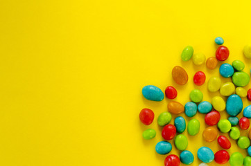 Multicolored candy on yellow background