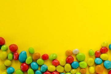 Multicolored candy on yellow background