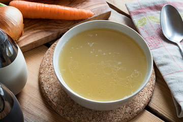 Chicken bone broth in a soup bowl on a table