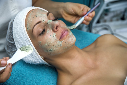 Cosmetician applying facial cream. Beautiful woman having a cosmetic treatment.