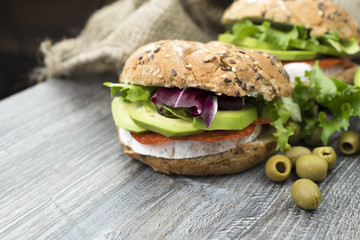 Sandwiches with avocado, camembert, vegetable salad and salami. Breakfast on the rustic table.