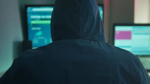 Male hacker internet working on a computer. man hacker in indoor hood hiding his Internet face