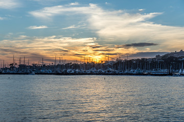 sunset radiated across the cloud turning it molten orange with bands of yellow above the boats at the harbor