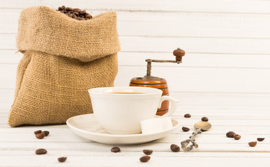 Fresh coffee concept with ceramic cup, jute bag and grinder