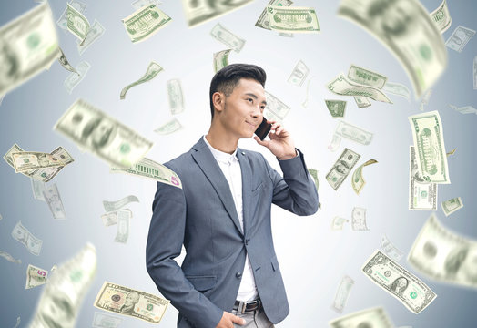 Asian businessman on phone, dollar rain