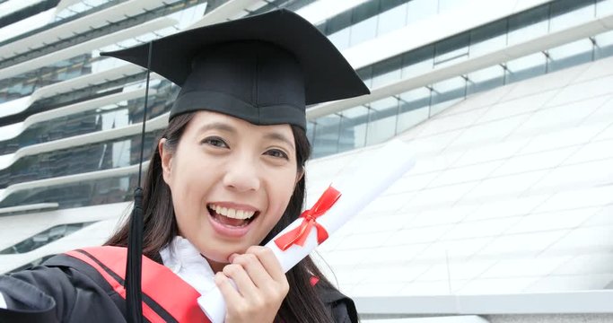 Cheerful woman wear graduation gown and make a video call