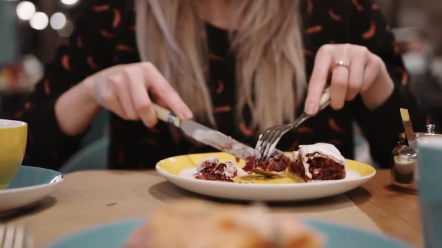 Unrecognizable girl eating dessert strudel at the restaurant using fork and knife. Slow motion.