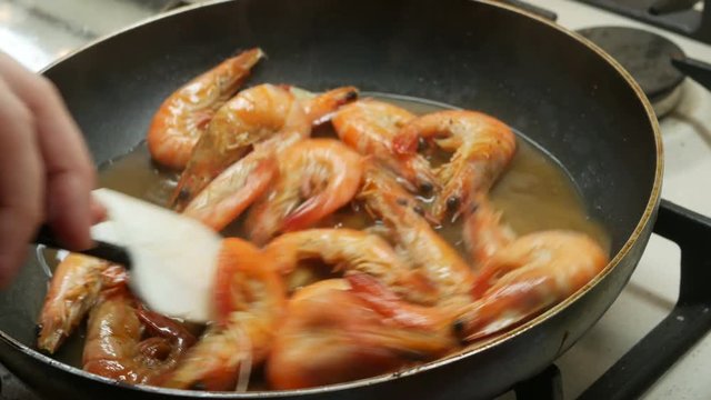 mixed large red shrimps are fried in hot boiled oil on pan, close-up