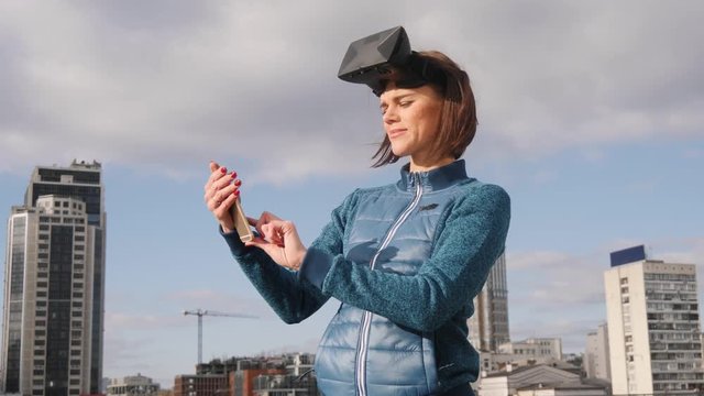 Virtual reality Girl uses vr head mounted display when texting sms or recieving call on phone. Slow motion.
