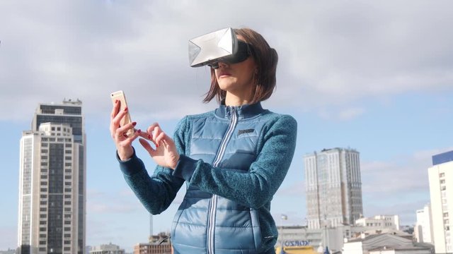 Virtual reality Girl uses vr head mounted display when texting sms or recieving call on phone. Slow motion.