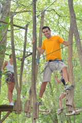 Naklejka na ściany i meble couple on a rope climbing in the adventure park