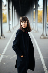 Female beauty concept. Portrait of fashionable young girl in casual black jacket posing on the street.