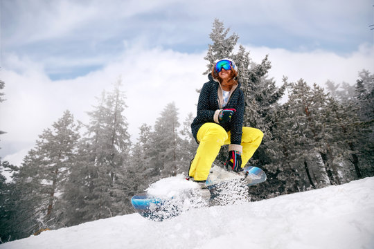 girl snowboarder in jump at ski resort in the mountain